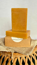 Handcrafted Turmeric Elixir Bar enriched with Vitamin C, displayed with turmeric roots, citrus slices, and natural botanical elements on a warm earthy background, highlighting a brightening natural skincare soap.